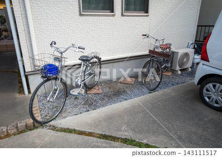 Bicycles lined up in the gravel area in front of the house Bicycles lined up in the gravel area in front of the house 143111517