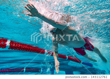 Swimmer pushing through bubbles with powerful movement. 143112761