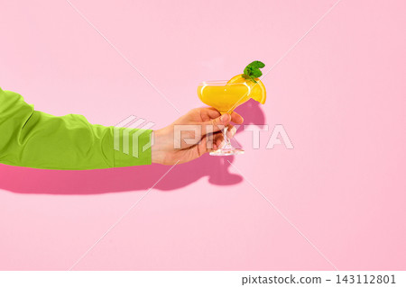 Hand holding orange cocktail on pink background with copy space. 143112801