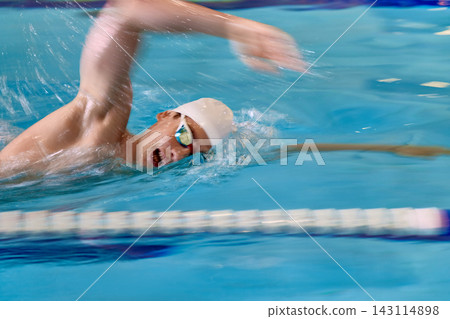 Swimmer moving fast through pool water with blurred freestyle stroke. Swimmer moving fast through pool water with blurred freestyle stroke. 143114898