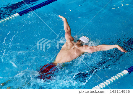 Male swimmer training backstroke technique in indoor pool lane. Male swimmer training backstroke technique in indoor pool lane. 143114936