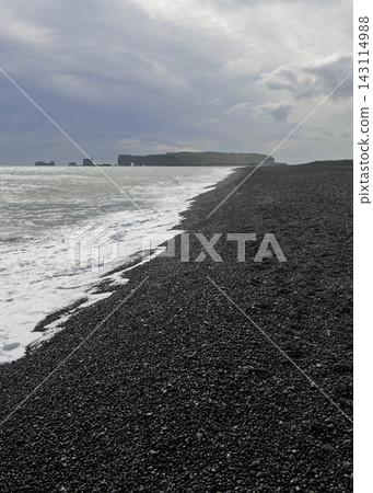 Atlantic surf on Reynisfjara pebble shore with distant Dyrholaey, Iceland Atlantic surf on Reynisfjara pebble shore with distant Dyrholaey, Iceland 143114988