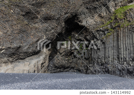 Curving basalt columns above black pebble shore at Reynisfjara Beach in Iceland 143114992