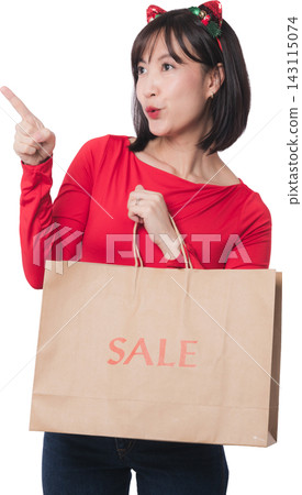 Excited young asian woman holding paper bag pointing up during christmas sale and black friday shopping event with cheerful mouth expression against transparency background 143115074