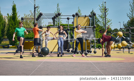 Group of young adults stretching at outdoor fitness park before workout. Group of young adults stretching at outdoor fitness park before workout. 143115950