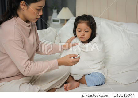 mother using thermometer measuring temperature to checking fever of sick preschoool child girl in bed mother using thermometer measuring temperature to checking fever of sick preschoool child girl in bed 143116044