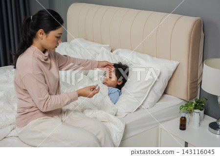 mother using thermometer measuring temperature to checking fever of sick preschoool child girl while hand touching forehead in bed mother using thermometer measuring temperature to checking fever of sick preschoool child girl while hand touching forehead in bed 143116045
