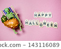 Skeleton Figurine Relaxing with Pumpkin on Pink Background 143116089