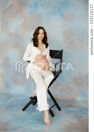 Pregnant Woman Sitting on Director's Chair in Studio Pregnant Woman Sitting on Director's Chair in Studio 143116117