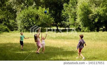 Children throwing ball in open meadow near trees. Children throwing ball in open meadow near trees. 143117051