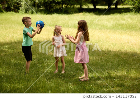 Children playing with blue ball in sunny green park Children playing with blue ball in sunny green park 143117052