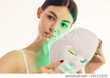 Beauty portrait of woman with green LED face mask and glowing skin Beauty portrait of woman with green LED face mask and glowing skin 143117079