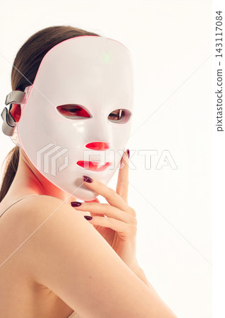 Close up woman wearing LED facial mask during beauty therapy routine Close up woman wearing LED facial mask during beauty therapy routine 143117084
