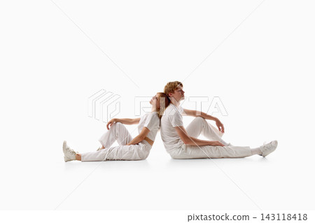 Young couple sitting back to back and stretching legs on white studio background Young couple sitting back to back and stretching legs on white studio background 143118418