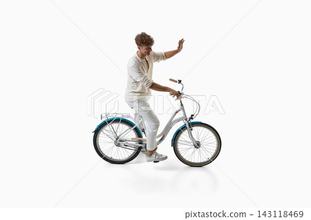 Smiling young man waves while standing beside bicycle Smiling young man waves while standing beside bicycle 143118469
