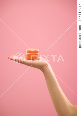 Cosmetic cream jar displayed on open palm against clean pink background Cosmetic cream jar displayed on open palm against clean pink background 143118957