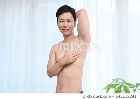一位微笑的男士正在檢查腋下除毛的效果。 143119241