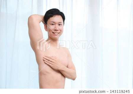 A smiling man checks the effectiveness of underarm hair removal. A smiling man checks the effectiveness of underarm hair removal. 143119245