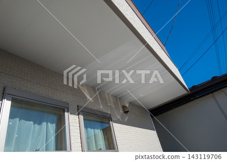 The exterior of the house with its white eaves stands out against the blue sky. The exterior of the house with its white eaves stands out against the blue sky. 143119706