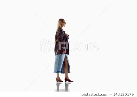 Woman displays side view of chic leather jacket and denim outfit Woman displays side view of chic leather jacket and denim outfit 143120179