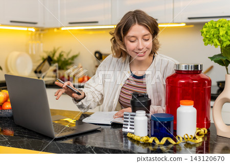Young woman writing fitness supplement list in notebook for diet plan and healthy workout nutrition Young woman writing fitness supplement list in notebook for diet plan and healthy workout nutrition 143120670