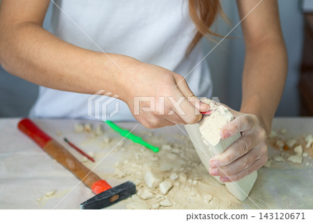 Young girl carving a small sculpture by hand with hammer and chisel at a worktable Young girl carving a small sculpture by hand with hammer and chisel at a worktable 143120671