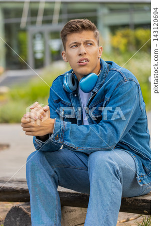 Young man feeling stress fatigue and worry in city street showing anxious serious portrait outdoors Young man feeling stress fatigue and worry in city street showing anxious serious portrait outdoors 143120694