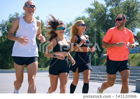 Fit adults running together in sunglasses during sunny recreational training Fit adults running together in sunglasses during sunny recreational training 143120996