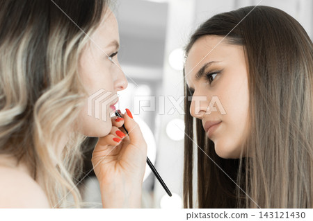 A skilled makeup artist carefully applies lipstick to a client, focusing on creating a flawless look. The scene captures the beauty and expertise involved in professional makeup application A skilled makeup artist carefully applies lipstick to a client, focusing on creating a flawless look. The scene captures the beauty and expertise involved in professional makeup application 143121430