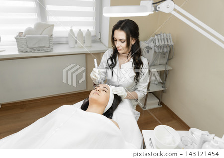 A woman receives a high tech facial procedure from a skilled esthetician in a clean, contemporary spa setting. The scene highlights beauty, wellness, and innovative skincare solutions A woman receives a high tech facial procedure from a skilled esthetician in a clean, contemporary spa setting. The scene highlights beauty, wellness, and innovative skincare solutions 143121454