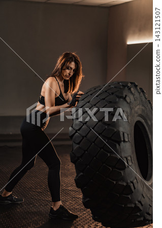 Confident woman performs functional strength exercise with heavy tire, showcasing dedication to healthy lifestyle. Motivational gym scene highlights endurance, empowerment for active individuals Confident woman performs functional strength exercise with heavy tire, showcasing dedication to healthy lifestyle. Motivational gym scene highlights endurance, empowerment for active individuals 143121507