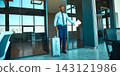 Excited male traveler holds documents beside a suitcase at airport doorway with joyful anticipation Excited male traveler holds documents beside a suitcase at airport doorway with joyful anticipation 143121986