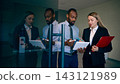 Corporate colleagues review a tablet and documents beside glass doors in airport with productive concentration Corporate colleagues review a tablet and documents beside glass doors in airport with productive concentration 143121989