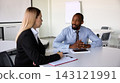 Male executive explains ideas to a businesswoman during airport meeting with serious confidence Male executive explains ideas to a businesswoman during airport meeting with serious confidence 143121991