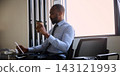 Business traveler reviews a tablet and drinks coffee in airport waiting area with calm concentration Business traveler reviews a tablet and drinks coffee in airport waiting area with calm concentration 143121993