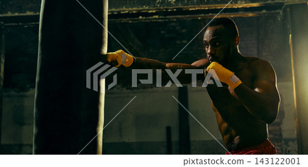 Skilled boxer lands a straight punch on a heavy bag with precise control Skilled boxer lands a straight punch on a heavy bag with precise control 143122001