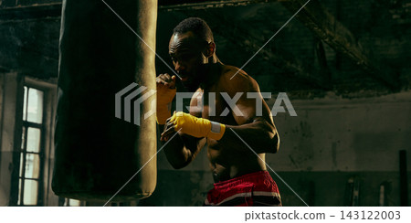 Dedicated fighter practices close-range punches on a heavy bag with relentless energy Dedicated fighter practices close-range punches on a heavy bag with relentless energy 143122003
