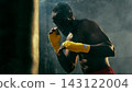 Concentrated combat athlete raises wrapped fists in a smoky gym with disciplined focus Concentrated combat athlete raises wrapped fists in a smoky gym with disciplined focus 143122004