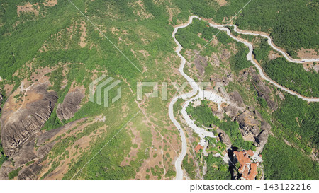 Horizontal aerial view of winding mountain serpentine road and monastery building among unique rock formations and green hills in Meteora Greece Horizontal aerial view of winding mountain serpentine road and monastery building among unique rock formations and green hills in Meteora Greece 143122216