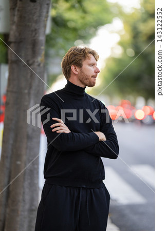 Man with black turtleneck looking away on city street Man with black turtleneck looking away on city street 143122552