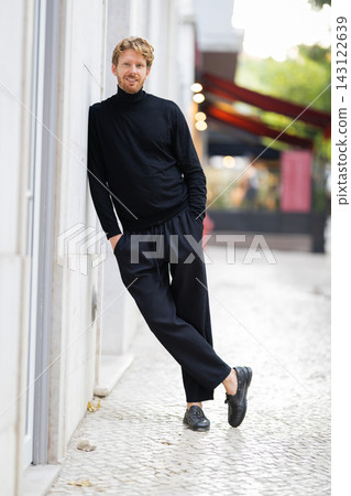 Man standing on street in black clothing with hands in pockets during daytime Man standing on street in black clothing with hands in pockets during daytime 143122639