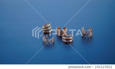 Small silver jewelry findings and metal components are grouped on a glossy blue surface with shallow depth of field. The compact composition symbolizes attention to detail, creativity, and artisan 143123052