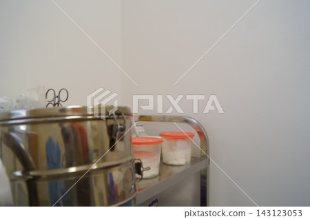 Sterile medical trolley with metal container and cotton jars in a clinic room. Healthcare preparation concept for hygiene, tools and clinical supplies Sterile medical trolley with metal container and cotton jars in a clinic room. Healthcare preparation concept for hygiene, tools and clinical supplies 143123053