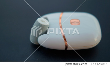 A compact white and blue wireless computer mouse with rose gold accents rests on a dark surface. The minimalist electronic device represents modern technology, digital productivity, and efficient A compact white and blue wireless computer mouse with rose gold accents rests on a dark surface. The minimalist electronic device represents modern technology, digital productivity, and efficient 143123066