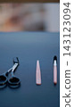 Black scissors, a slim pink grooming tool, and a small brush are arranged on a dark tabletop. Minimal grooming accessories symbolize personal care, precision, and everyday beauty routine. 143123094