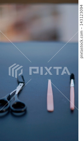 Black scissors, a slim pink grooming tool, and a small brush are arranged on a dark tabletop. Minimal grooming accessories symbolize personal care, precision, and everyday beauty routine. Black scissors, a slim pink grooming tool, and a small brush are arranged on a dark tabletop. Minimal grooming accessories symbolize personal care, precision, and everyday beauty routine. 143123094