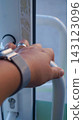 Close-up of a person's hand pulling a curved metal handle on a self-service storage locker door. The image represents personal access, security, and the convenience of using automated storage 143123096