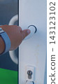 Close-up of a person's hand pressing a round control on the door of a self-service storage locker. The image represents secure interaction, access control, and simple automated storage technology. 143123102