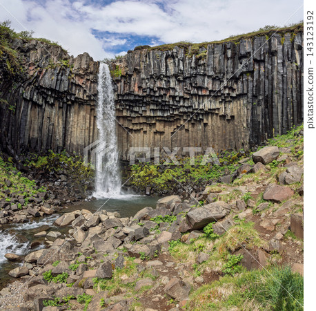 Svartifoss waterfall framed by a broad basalt amphitheater in Iceland with rocky foreground Svartifoss waterfall framed by a broad basalt amphitheater in Iceland with rocky foreground 143123192