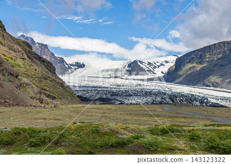 Skaftafellsjokull glacier tongue between rocky mountains under blue summer sky Skaftafellsjokull glacier tongue between rocky mountains under blue summer sky 143123322